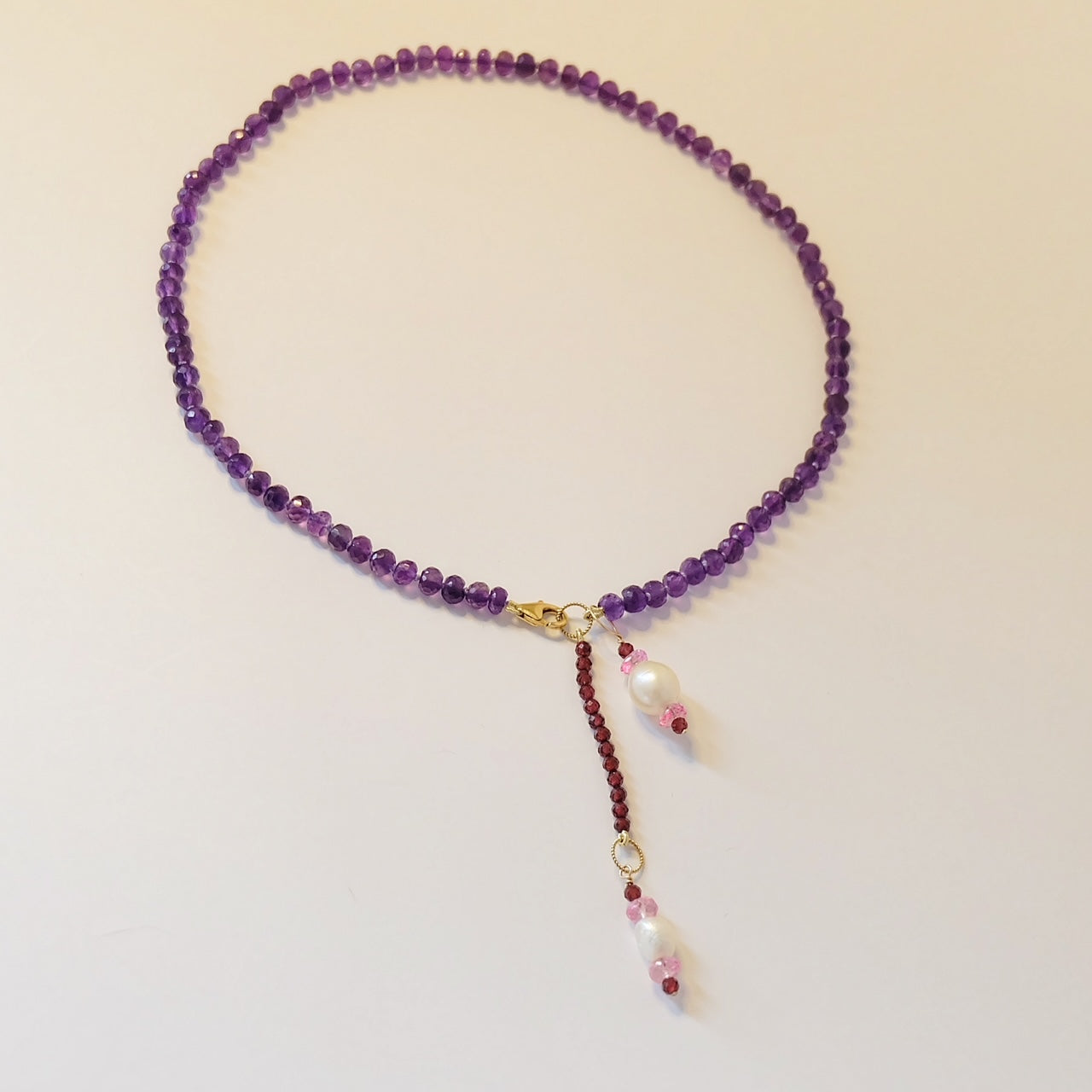 Beautiful amethyst necklace embellished with pearl and topaz charms, highlighting a luxurious and stylish accessory choice.