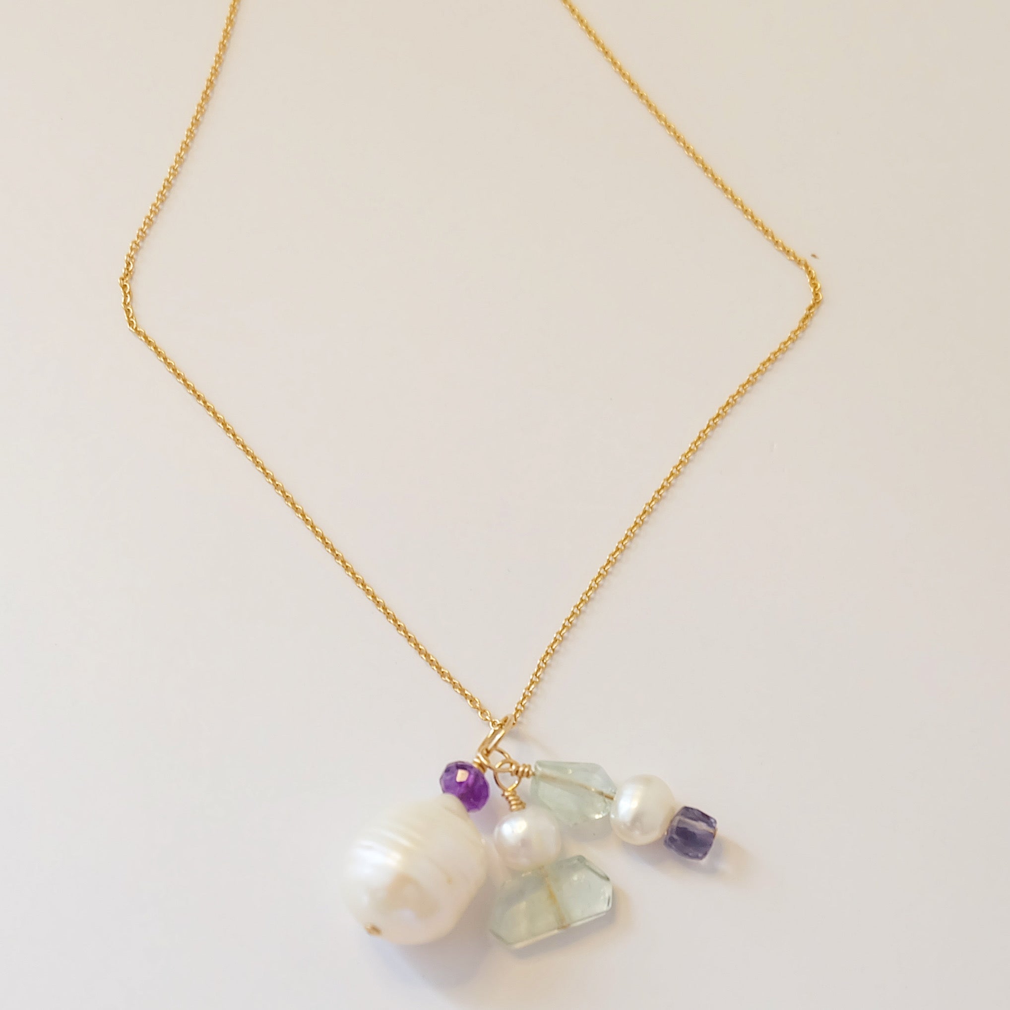 A delicate charm necklace featuring pearls, amethyst, and aquamarine, showcasing elegance and vibrant colors.