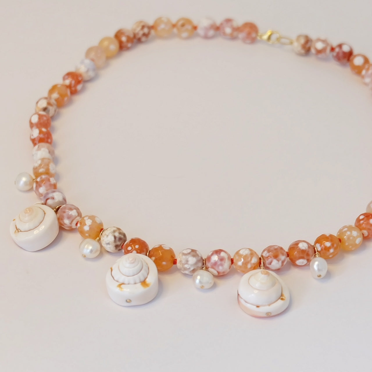 Pearl Agate Seashell Charm Necklace with unique hand-forged charms, elegantly knotted on silk, perfect for a coastal aesthetic.