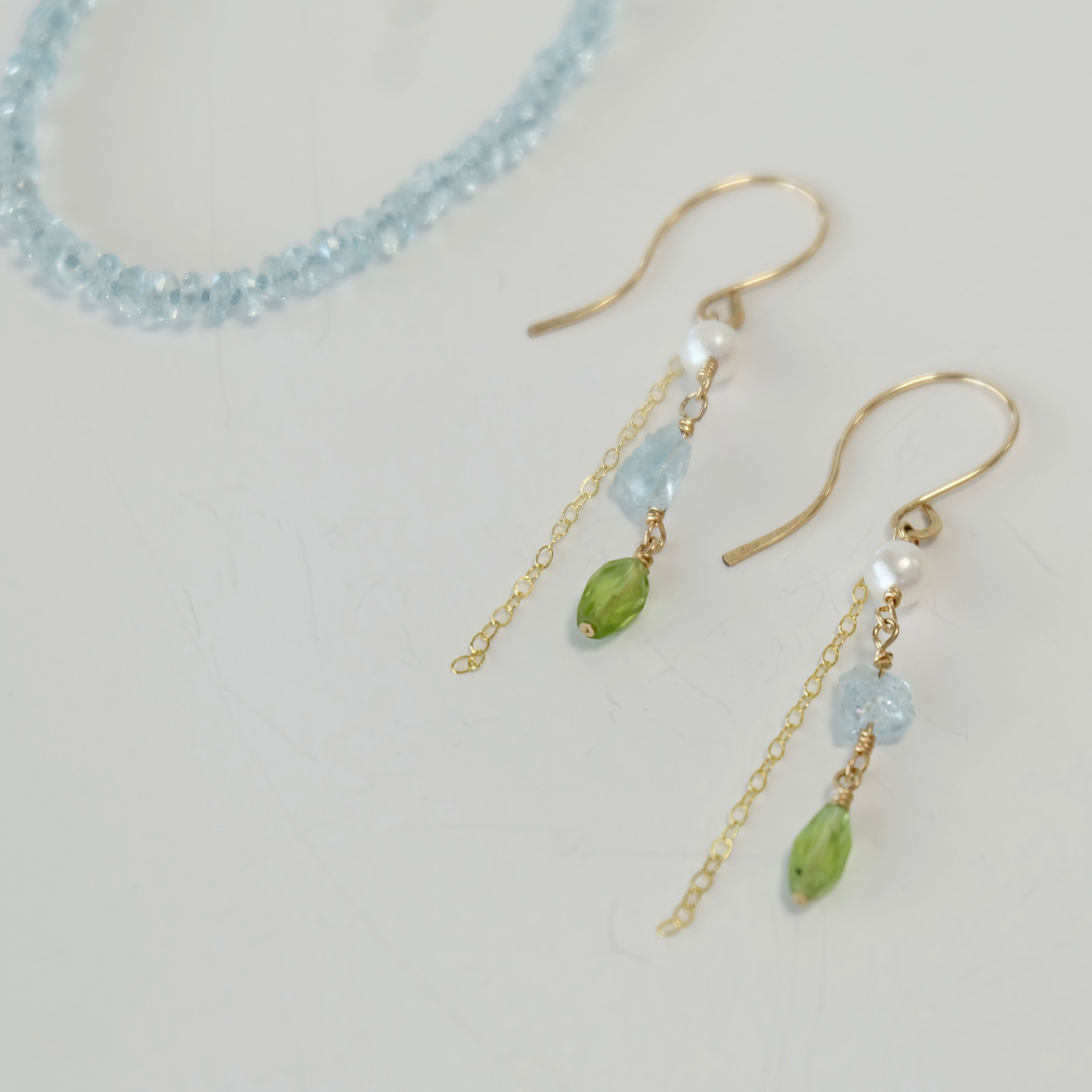 Aquamarine, Peridot & Pearl Dangle Earrings handcrafted with 14K gold-filled wire with green and blue beads on a light gray background