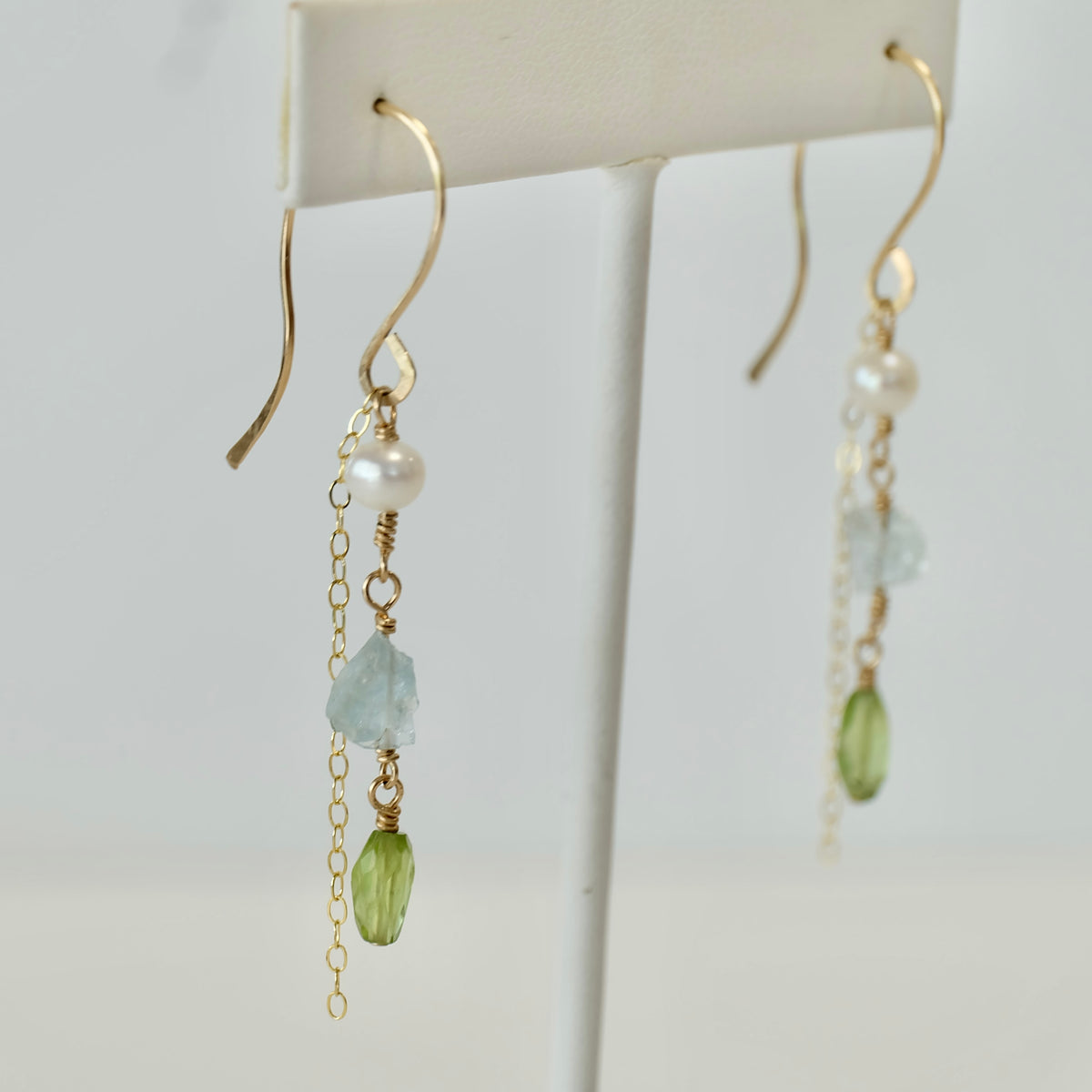 Close-up of aquamarine, peridot and freshwater pearl beads on gold-filled dangle earrings