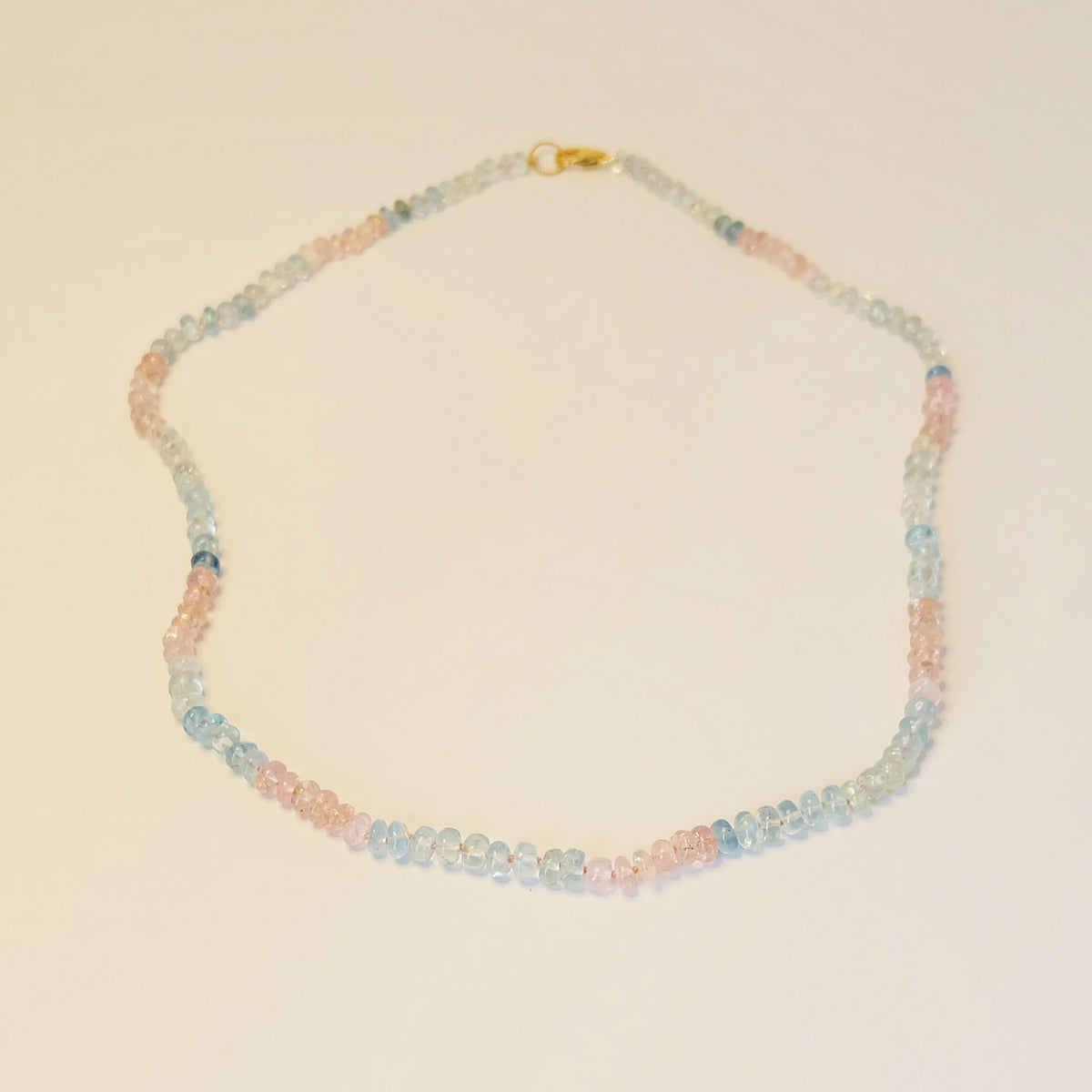 Flat-lay of pastel gemstone necklace featuring aquamarine and rose quartz, elegantly arranged to highlight smooth 6-7mm beads and delicate gold accents.