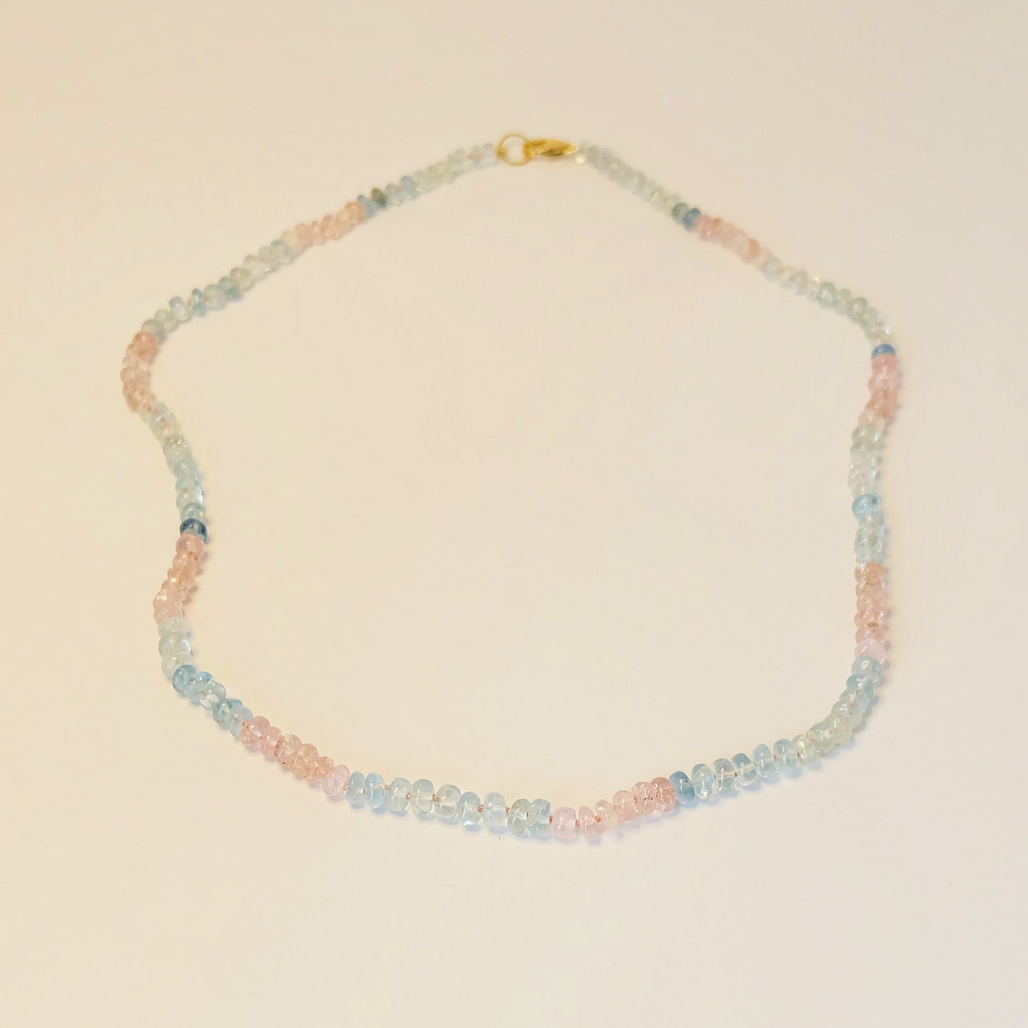 Flat-lay of pastel gemstone necklace featuring aquamarine and rose quartz, elegantly arranged to highlight smooth 6-7mm beads and delicate gold accents.