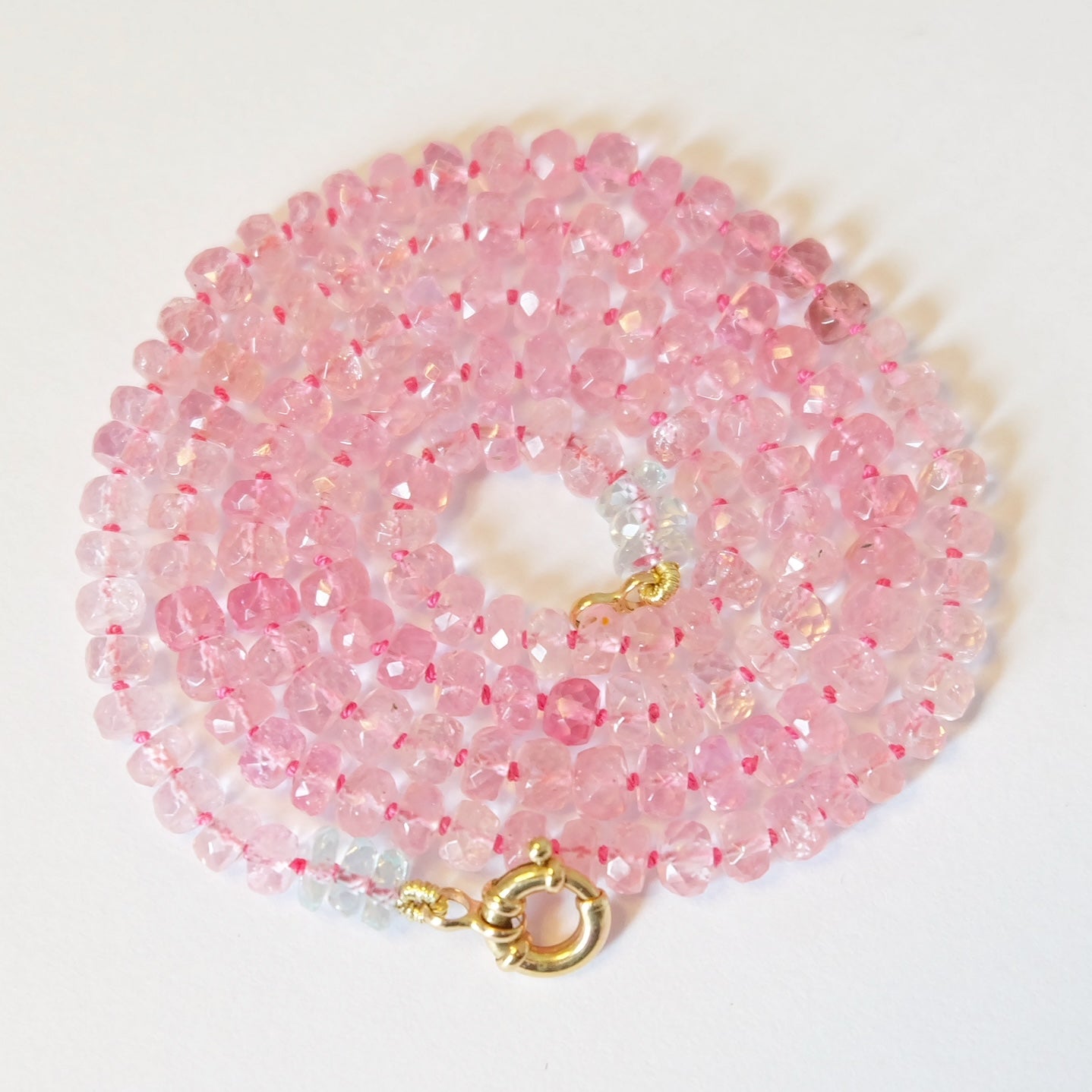 Display of pink tourmaline beaded candy necklace in 14k gold with hand-knotted silk and Burmese gemstones.