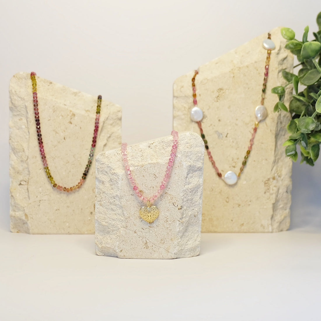 A collection of handcrafted tourmaline jewelry featuring green, pink, and blue gemstones.