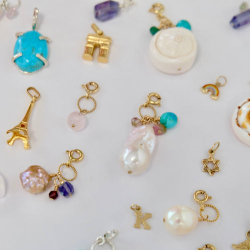 A collection of colorful charms displayed on a soft surface, showcasing various shapes and designs for jewelry making.