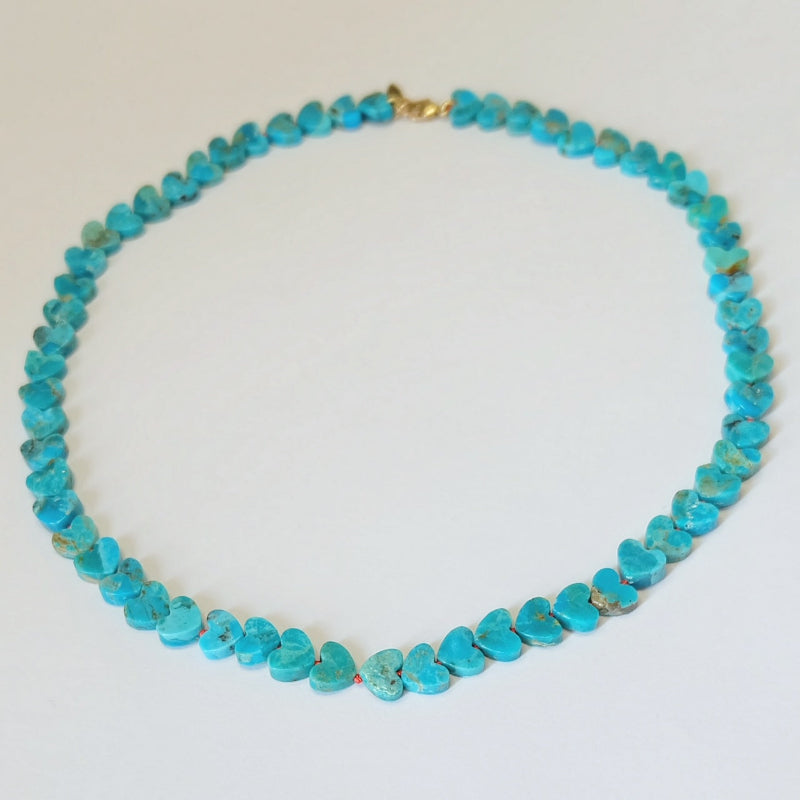Full strand view of a 14K gold Kingman turquoise heart necklace hand-knotted on burnt orange silk.