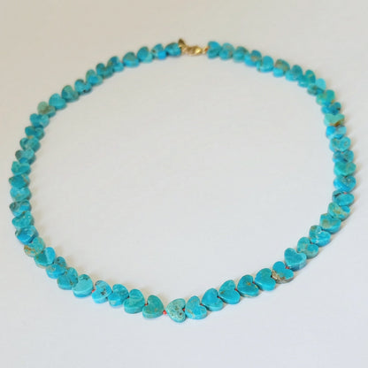 Full strand view of a 14K gold Kingman turquoise heart necklace hand-knotted on burnt orange silk.
