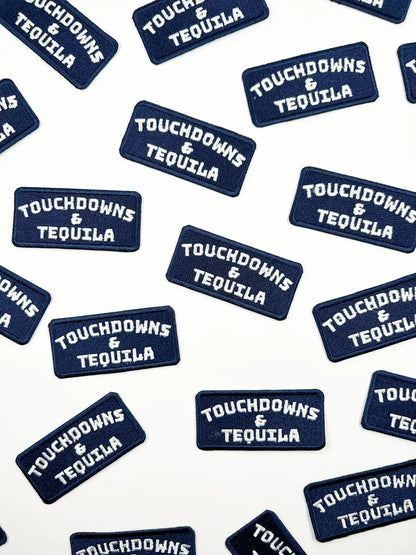 Multiple navy blue rectangular embroidered patches with white text reading 'TOUCHDOWNS & TEQUILA' scattered on a white background.
