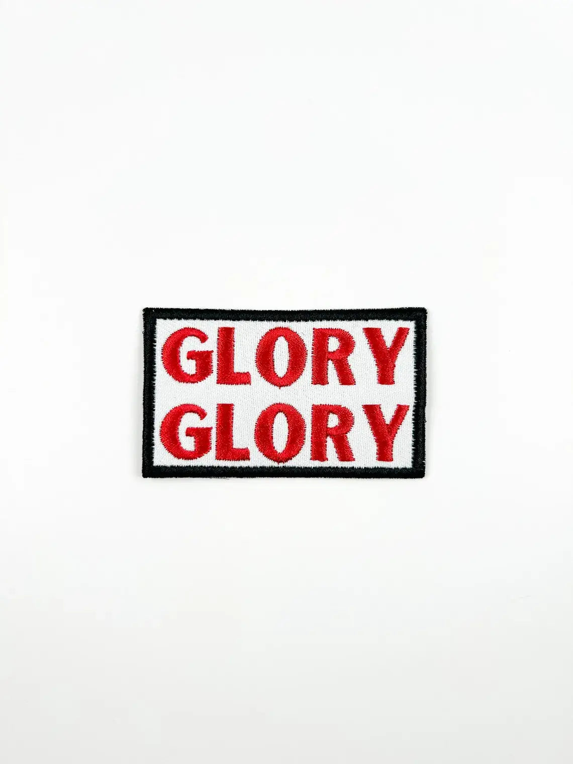 A rectangular embroidered patch with the word 'GLORY' repeated twice in red letters on a white background, bordered by black and white with a black outer border.