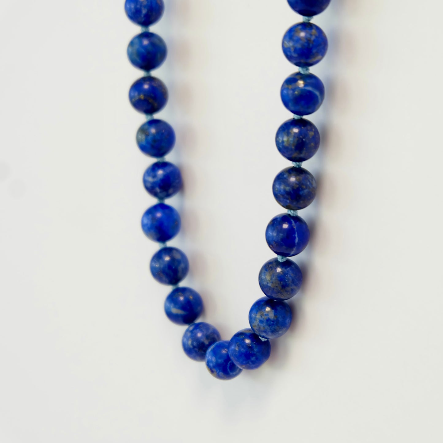  A striking knotted necklace adorned with lapis beads, offering a rich blue color and a chic, artisanal flair.