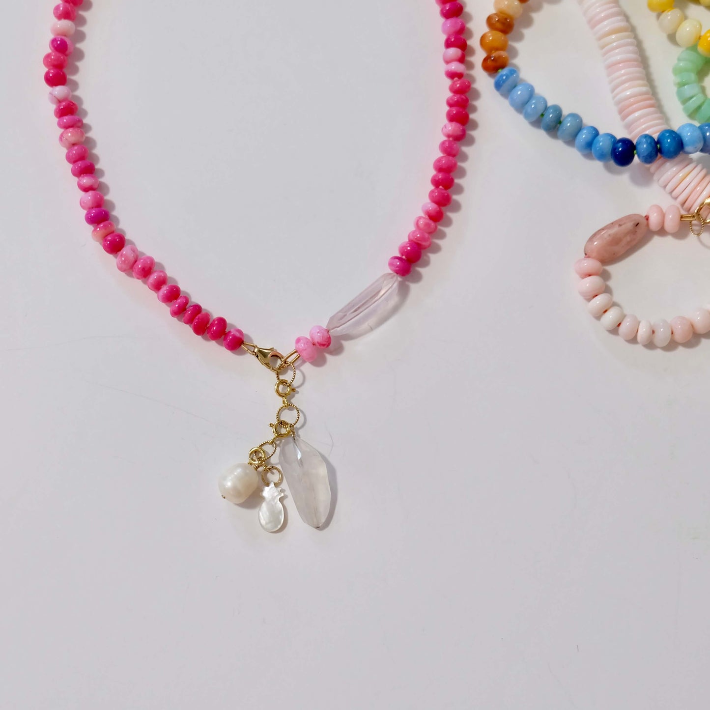 Beaded necklace with pink and gold accents on a light gray background