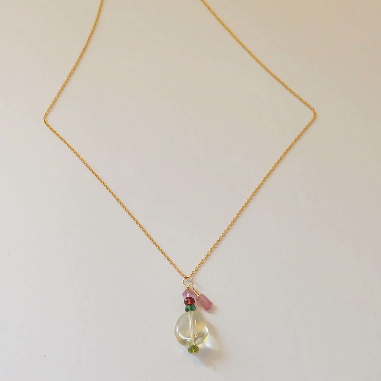 Gold charm necklace with green amethyst and tourmaline.