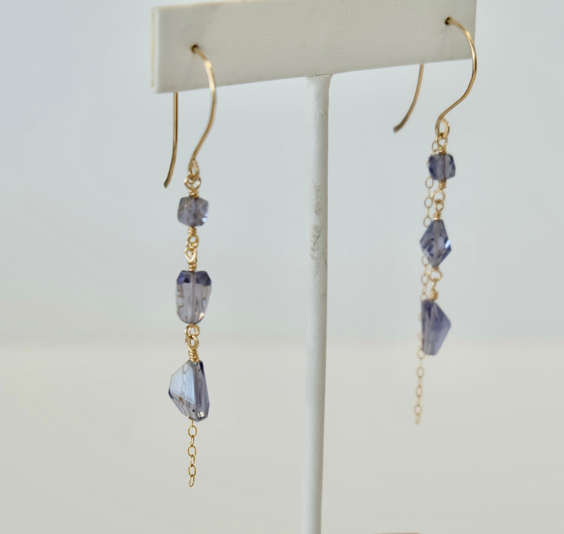 Iolite Gold dangle earrings with purple gemstones on a white background