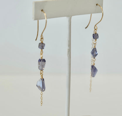 Iolite Gold dangle earrings with purple gemstones on a white background