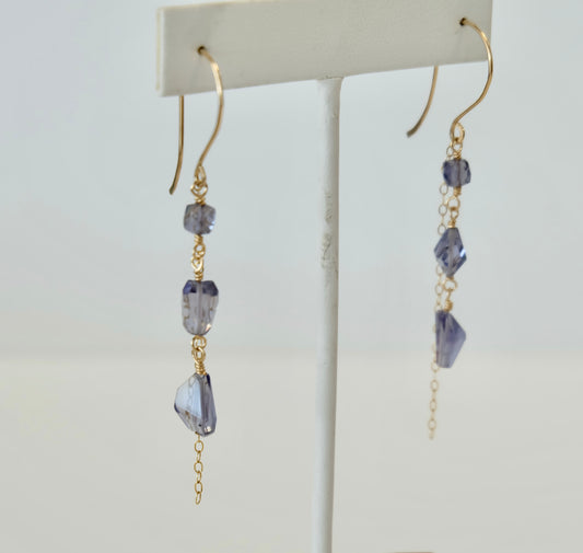 Iolite Gold dangle earrings with purple gemstones on a white background