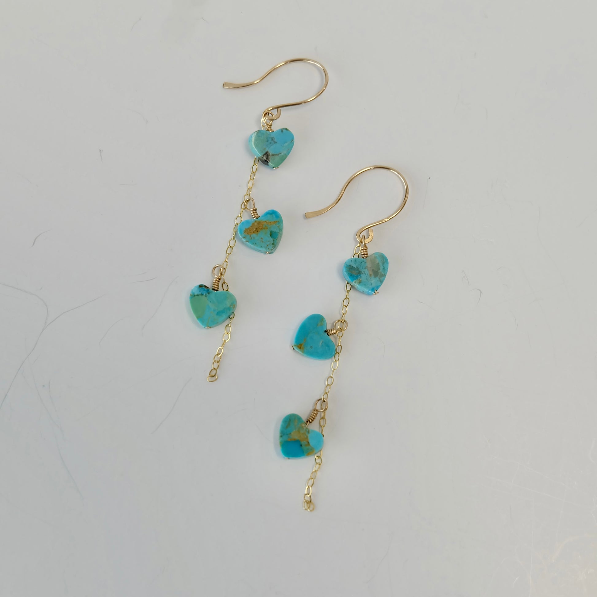 Display of Kingman turquoise heart angle earrings in 14K gold. 