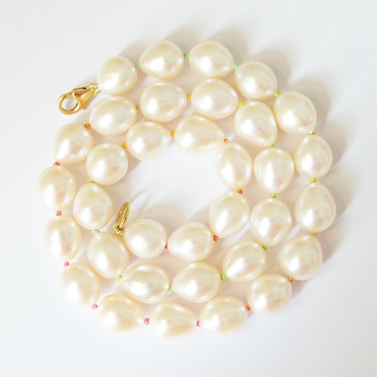 A stunning pearl necklace on rainbow silk thread.