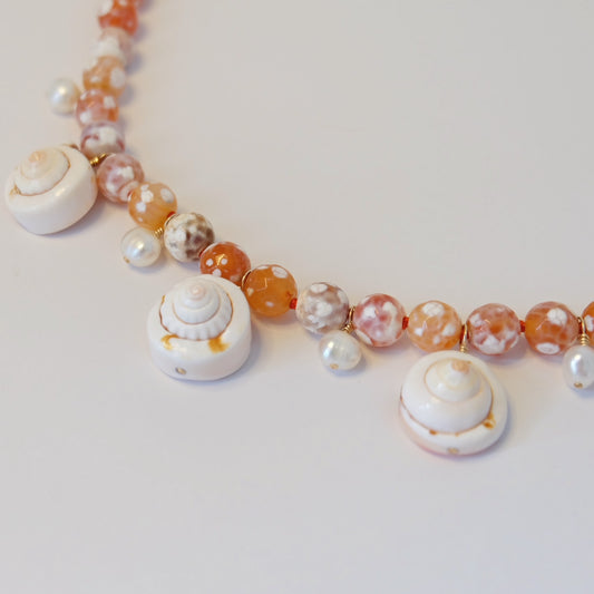 Discover the Pearl Agate Seashell Charm Necklace, showcasing hand-forged charms elegantly knotted on silk for coastal charm.