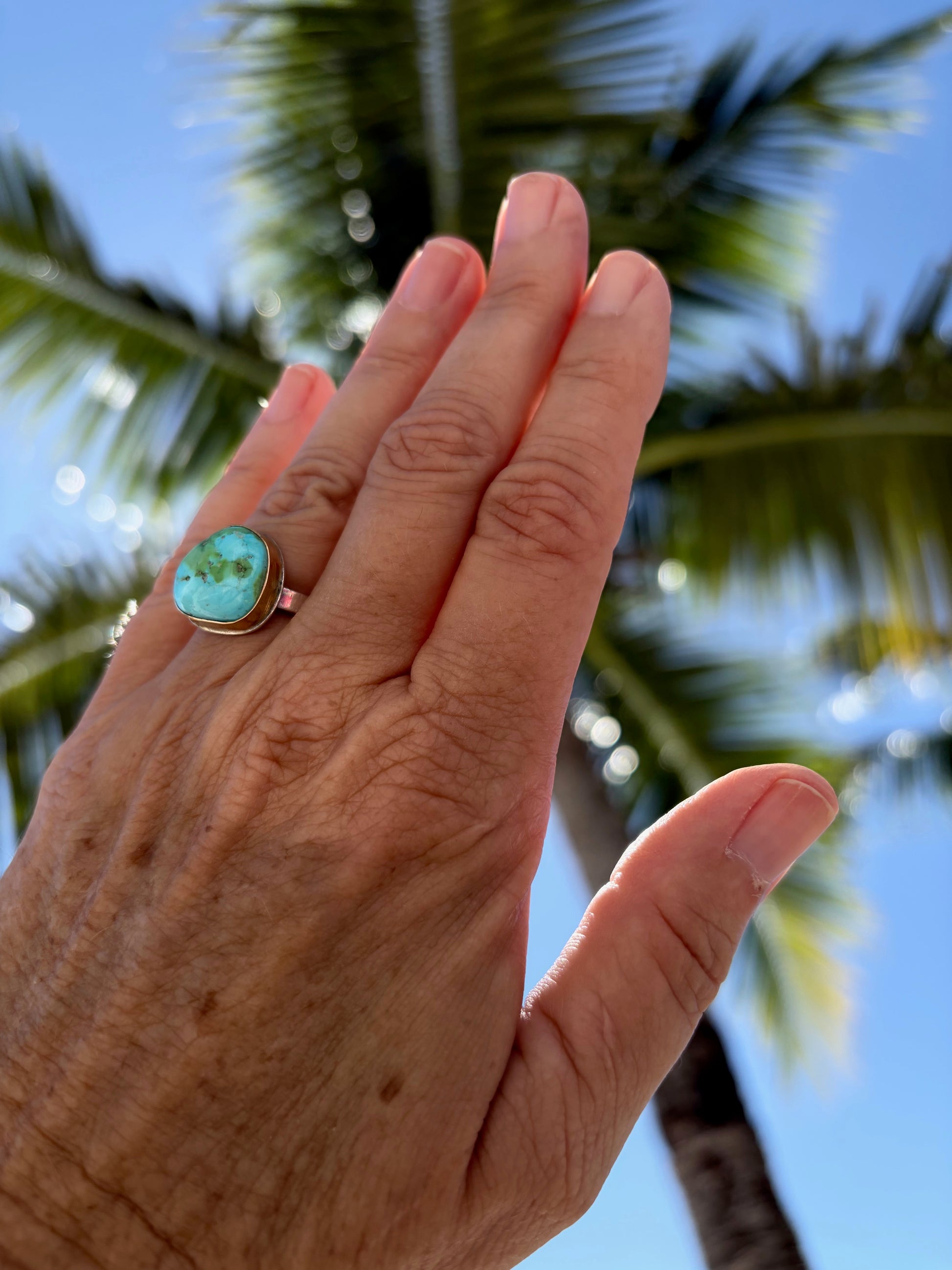Woman's hand wearing a sonora gold turquoise ring with sterling silver and gold