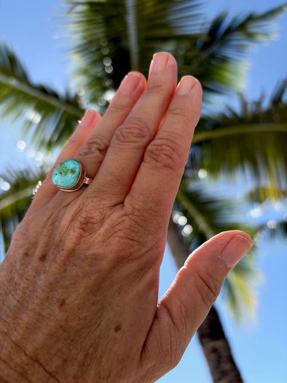 Woman's hand wearing a sonora gold turquoise ring with sterling silver and gold