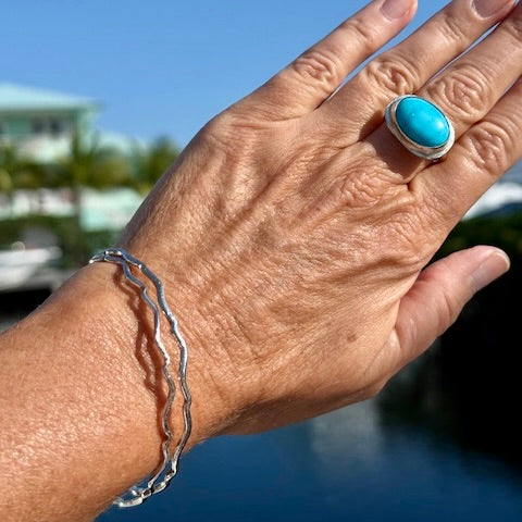 A wavy bangle with a smooth, flowing design, showcasing a shiny metallic finish and elegant curves.