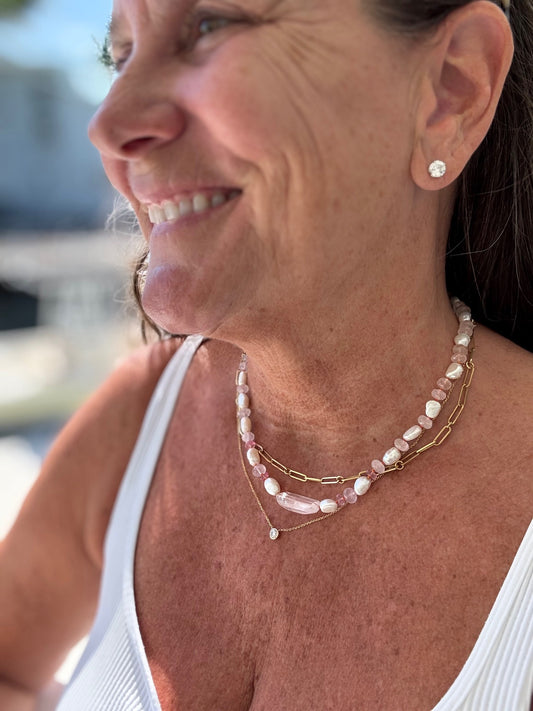 Woman wearing an eElegant candy necklace adorned with pink topaz, rose quartz, and pearl, showcasing a harmonious blend of soft colors.