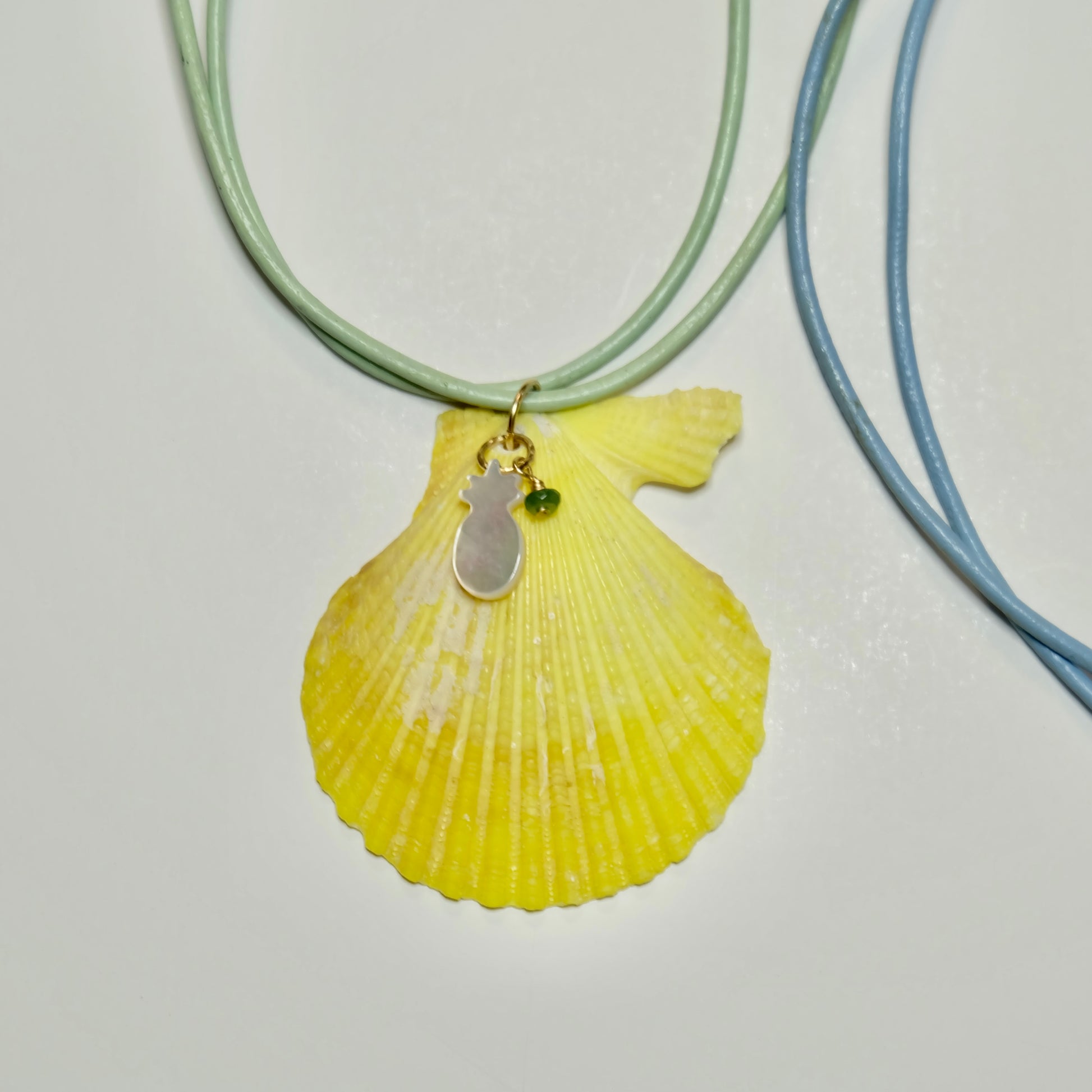 Yellow shell pendant necklace on a light gray background