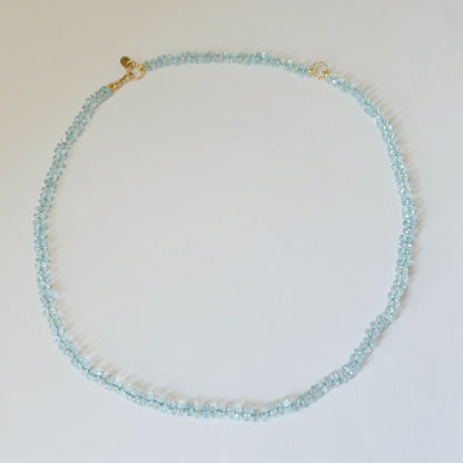 Flat lay view of a circular aquamarine candy necklace with solid 14K gold components.