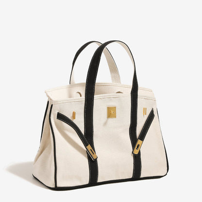 Side view of black Boatkin tote bag with gold hardware on a white background.