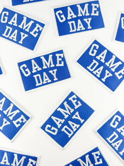 Blue and white 'GAME DAY' stickers scattered on a white background