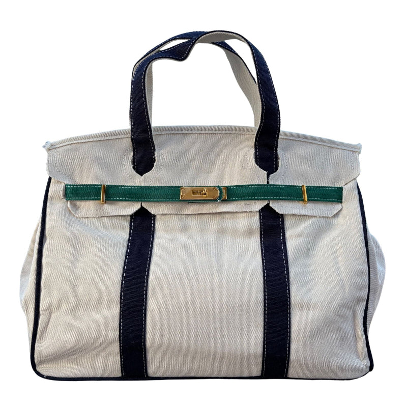 Front studio view of the cream canvas Boatkin tote bag featuring deep navy blue straps and forest green horizontal accents.