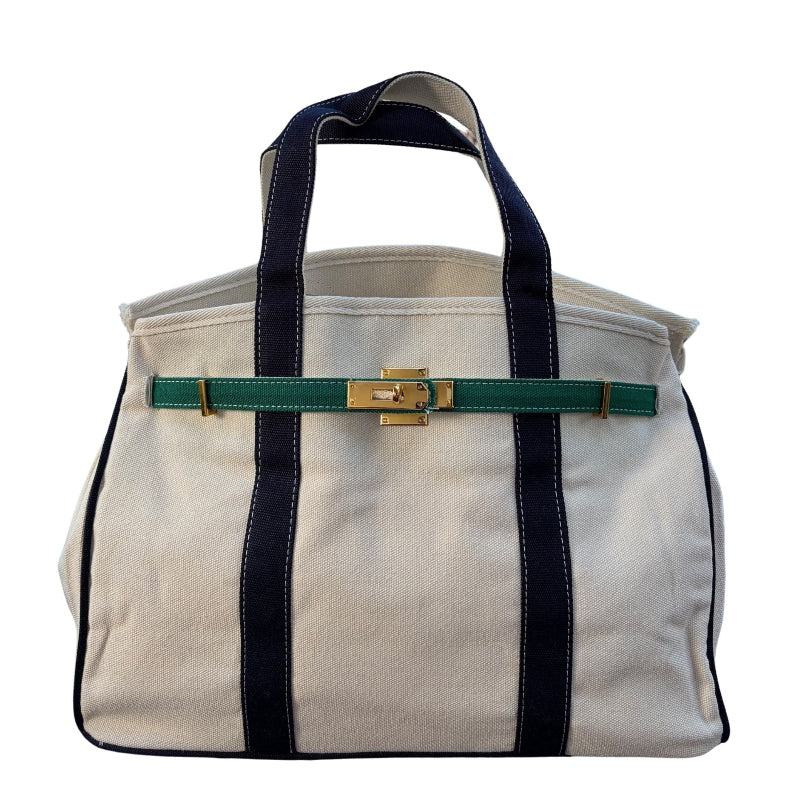Straight front view of the cream canvas Boatkin tote bag featuring navy blue vertical straps and a forest green belt horizontal strap.