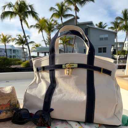 Navy Boatkin bag on a boat deck with palm trees and houses in the background
