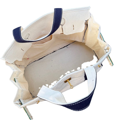 Close up angled look inside an open cream canvas Boatkin tote bag showing the light blue liner and gold hardware hook.
