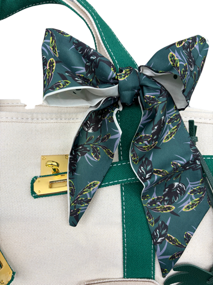 Green botanical leaf print twilly scarf tied in a bow on the handle of the Charleston canvas tote bag with gold hardware