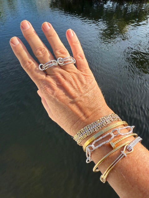 Woman's hand showing an assortment of braided interlocking rings.
