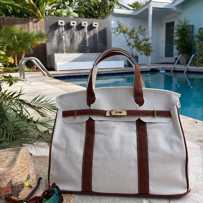 Brown Boatkin tote by a pool with a house and palm trees in the background.