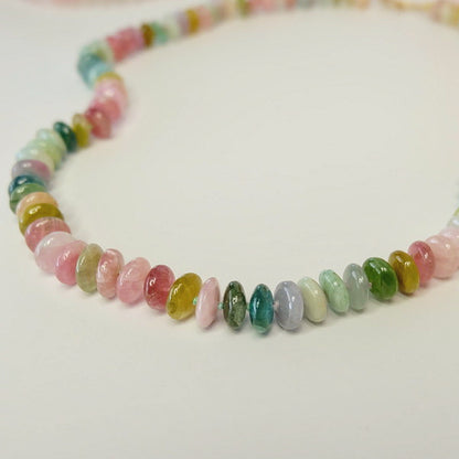 Close up of 14K gold watermelon tourmaline candy necklace beads on a white background.