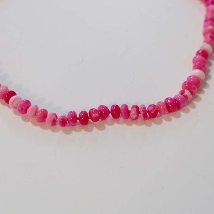 Close up of hot pink candy necklace beads on a  white background