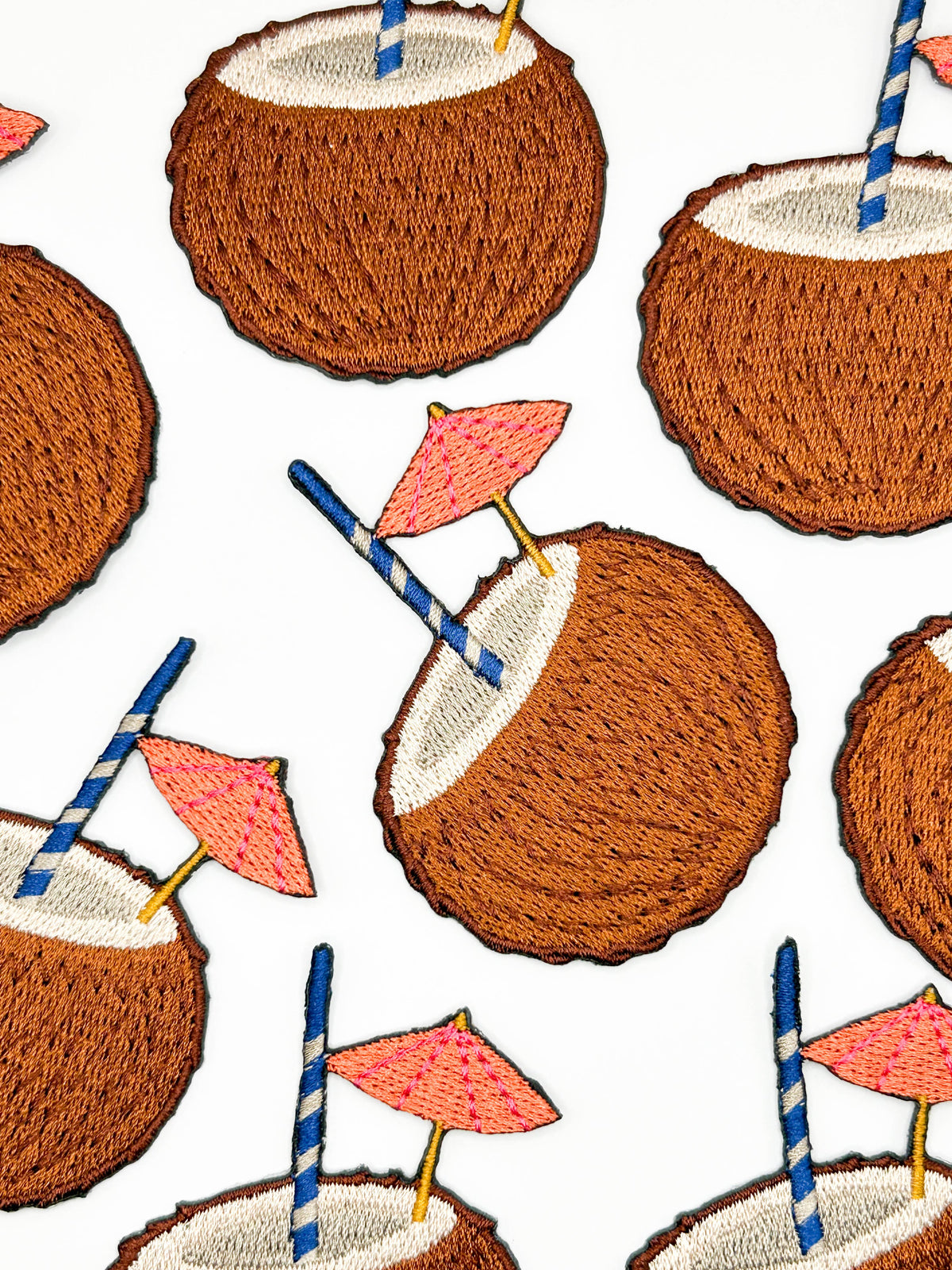 Coconut drink patch with blue striped straw and pink cocktail umbrella