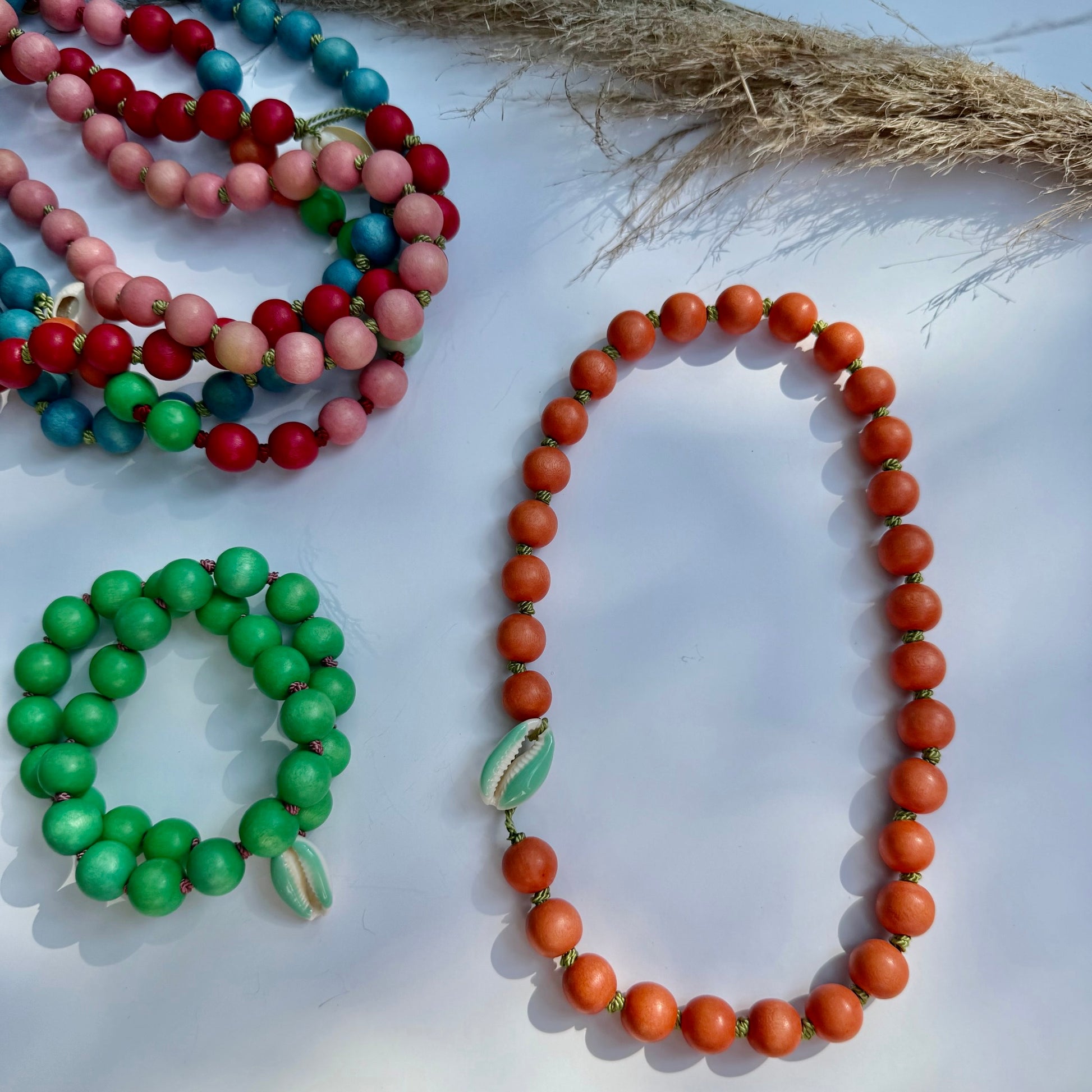 Colorful wood beaded necklaces on a white surface with a natural fiber background