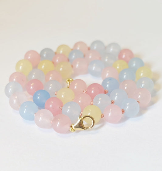 A close-up of the Cotton Candy Necklace featuring pastel pink, blue, and yellow beads hand-knotted on pale pink silk.