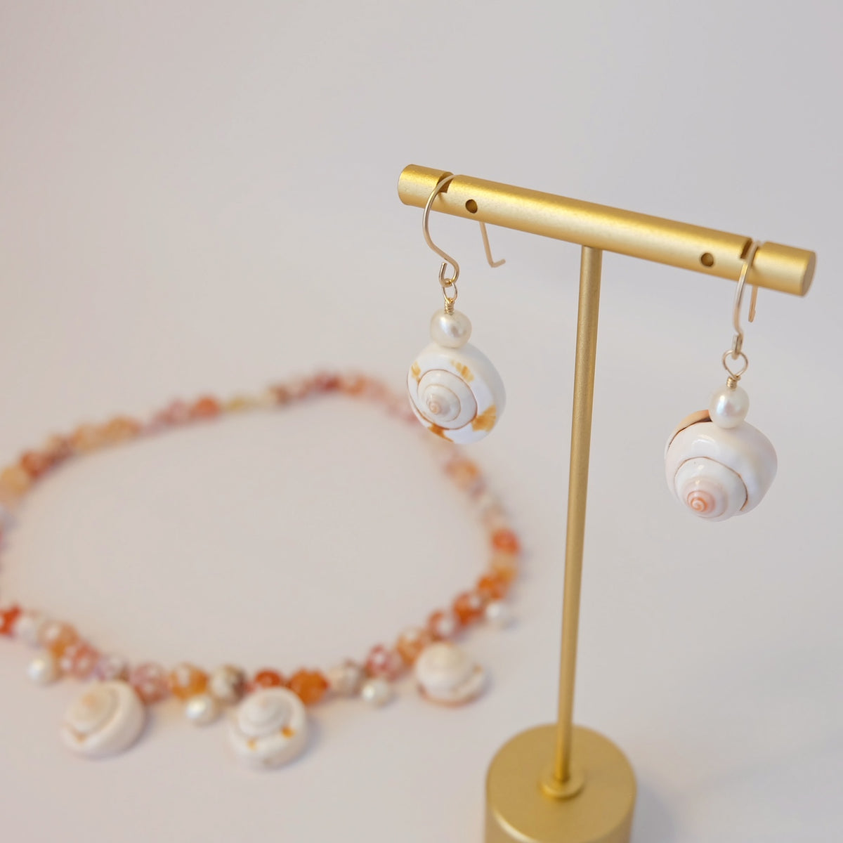 Close-up of cowrie shell and pearl dangle earrings