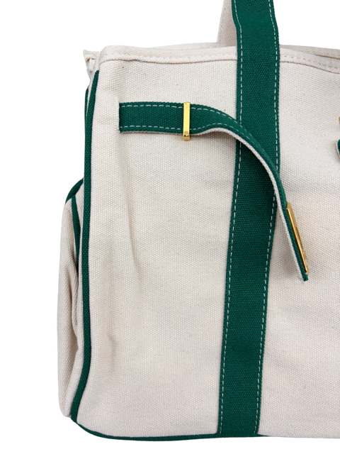 Side detail of the Charleston cream canvas tote bag showing green webbing trim, contrast stitching and gold-tipped strap
