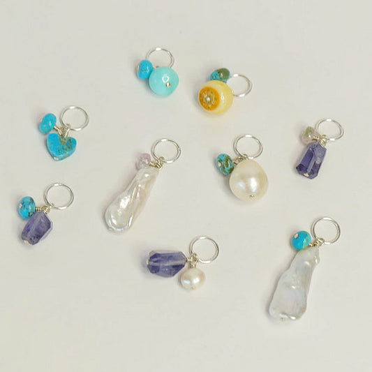 A collection of sterling silver charms adorned with colorful gemstones, showcasing their unique designs and sparkling beauty.