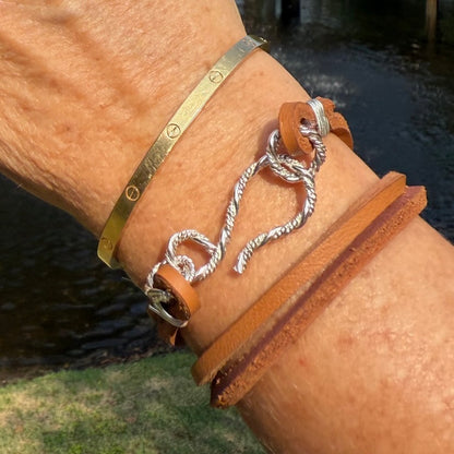 Close-up of the hand-forged sterling silver S-clasp on a brown leather bracelet