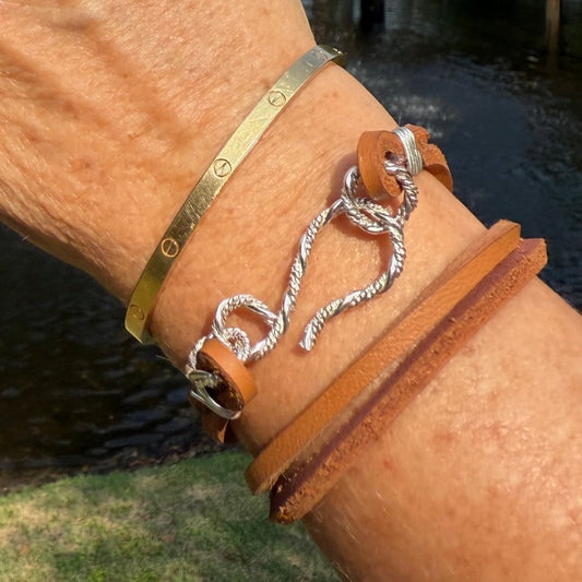 Close-up of the hand-forged sterling silver S-clasp on a brown leather bracelet