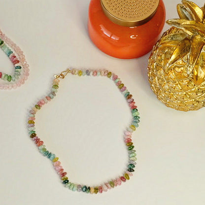 Flat lay of 14K gold watermelon tourmaline candy necklace displayed on a white background.