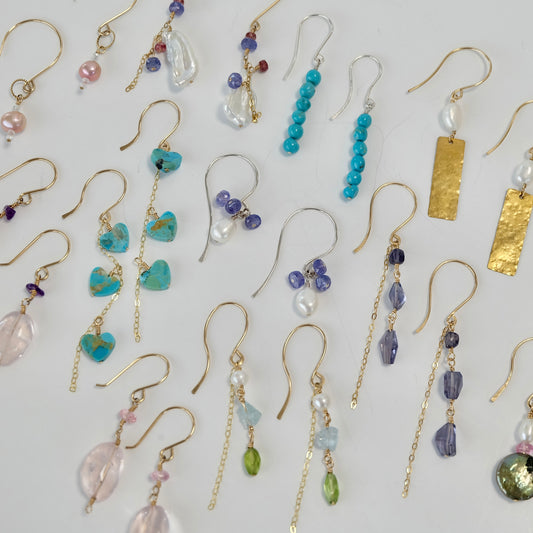 Collection of gold gemstone dangle earrings with different designs and colors on a light background